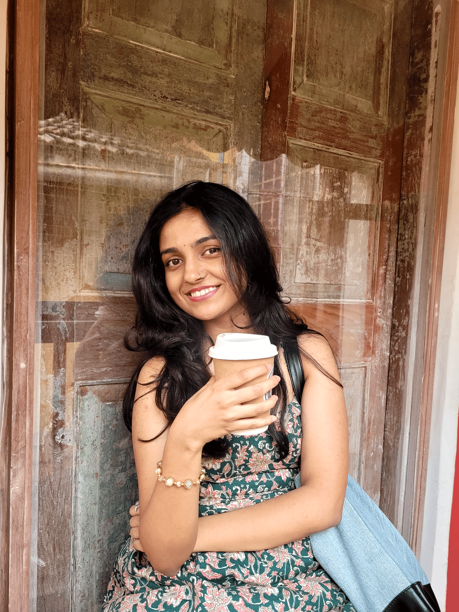 Nakshatra holding a coffee cup beside a wooden doorway